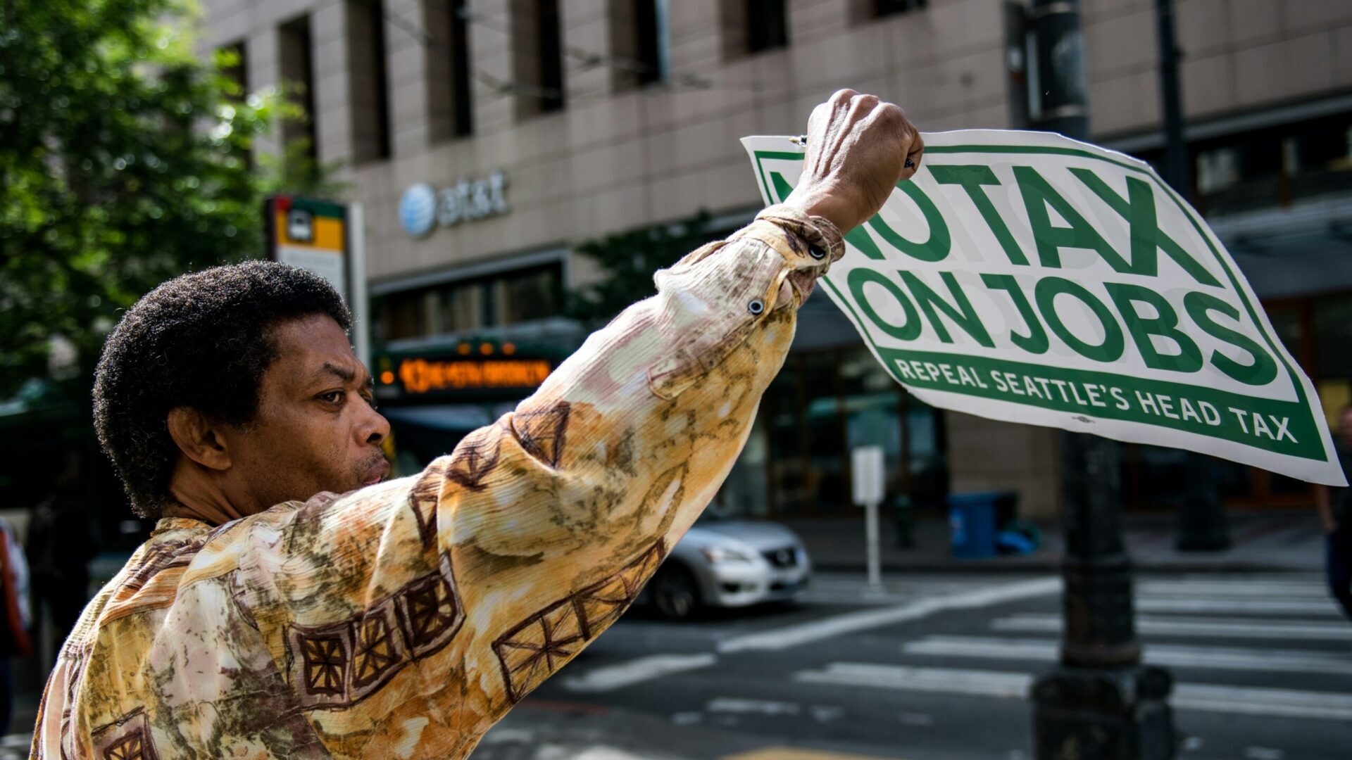 Person holding a protest sign that reads “NO TAX ON JOBS”
