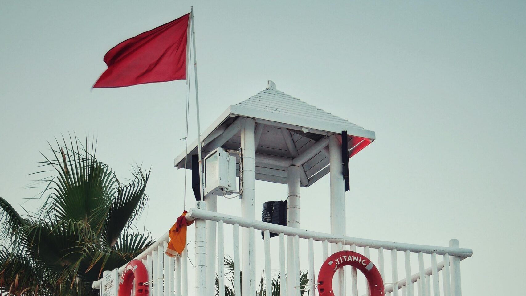 Lifeguard tower on a beach with safety flags and rescue equipment indicating monitored swimming conditions