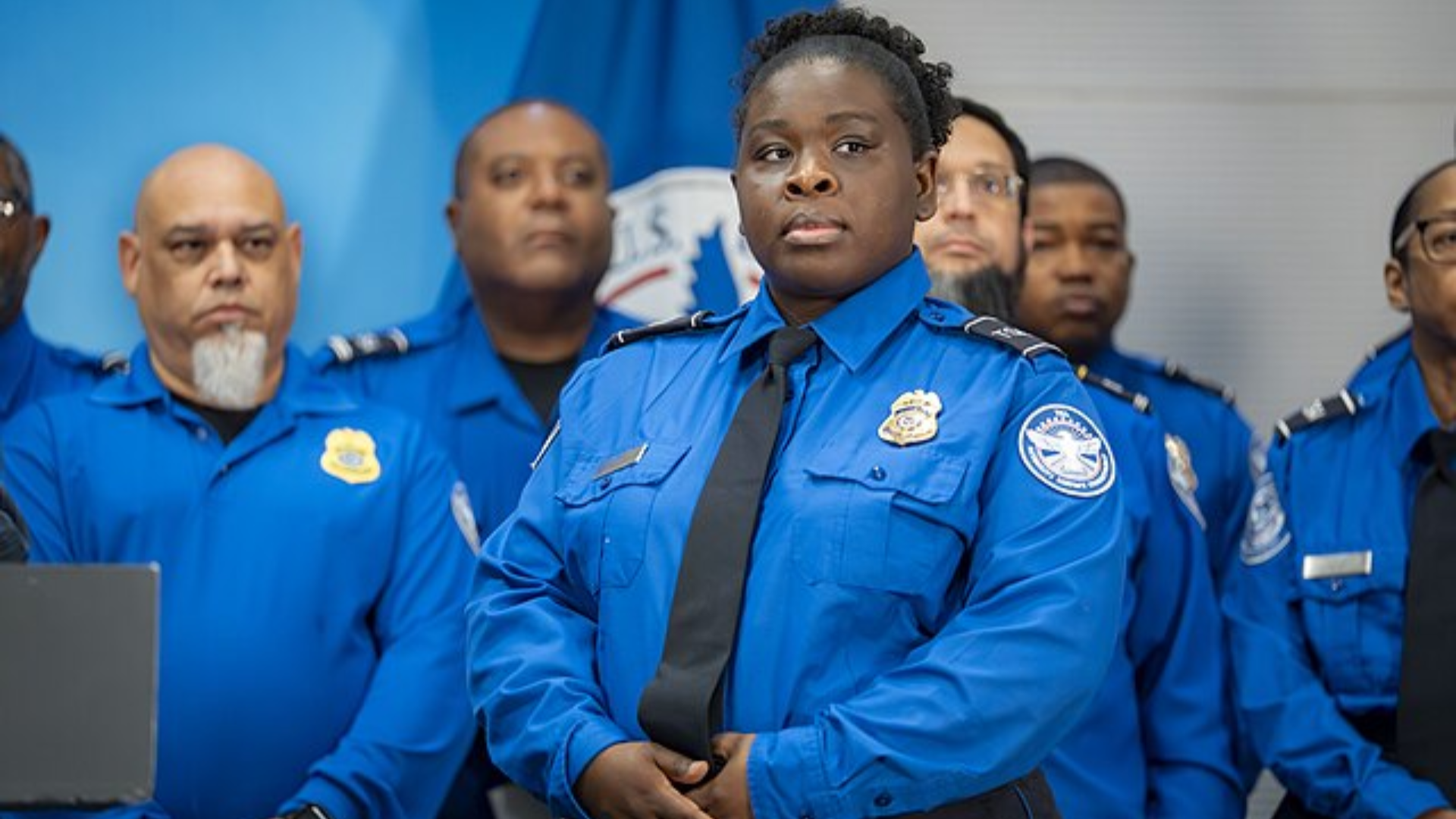 Group of TSA officers in blue uniforms standing together during a formal briefing.