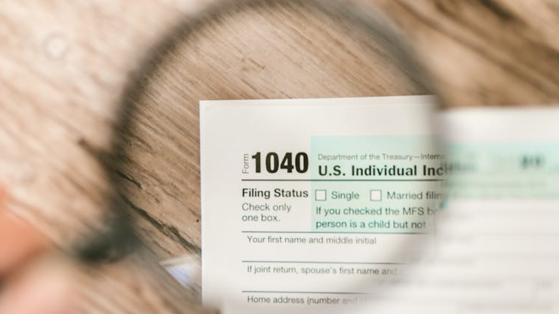 A magnifying glass shows a close up view of a printed tax form.