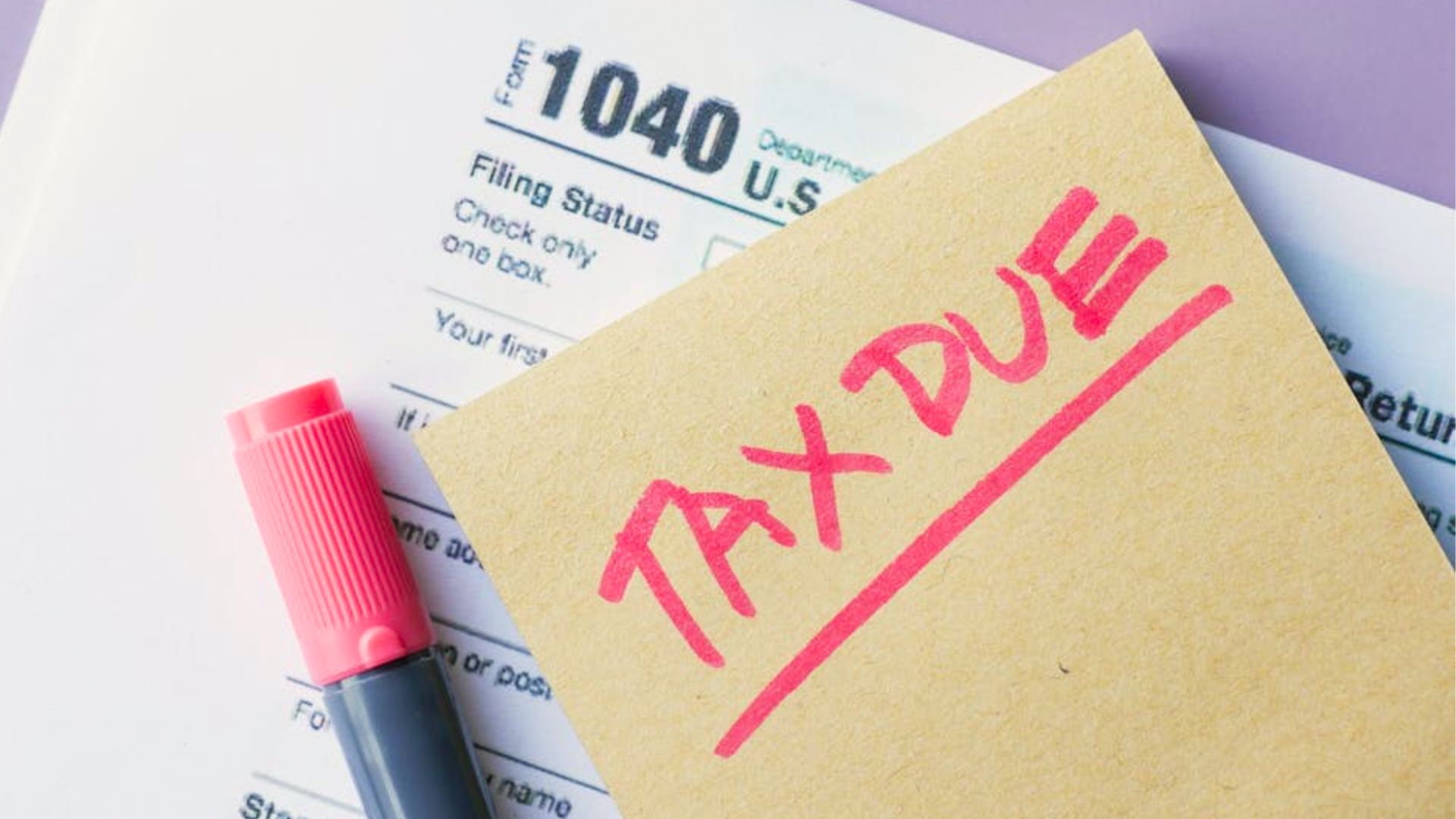 A sticky note saying "TAX DUE" in red marker rests on top of tax papers.