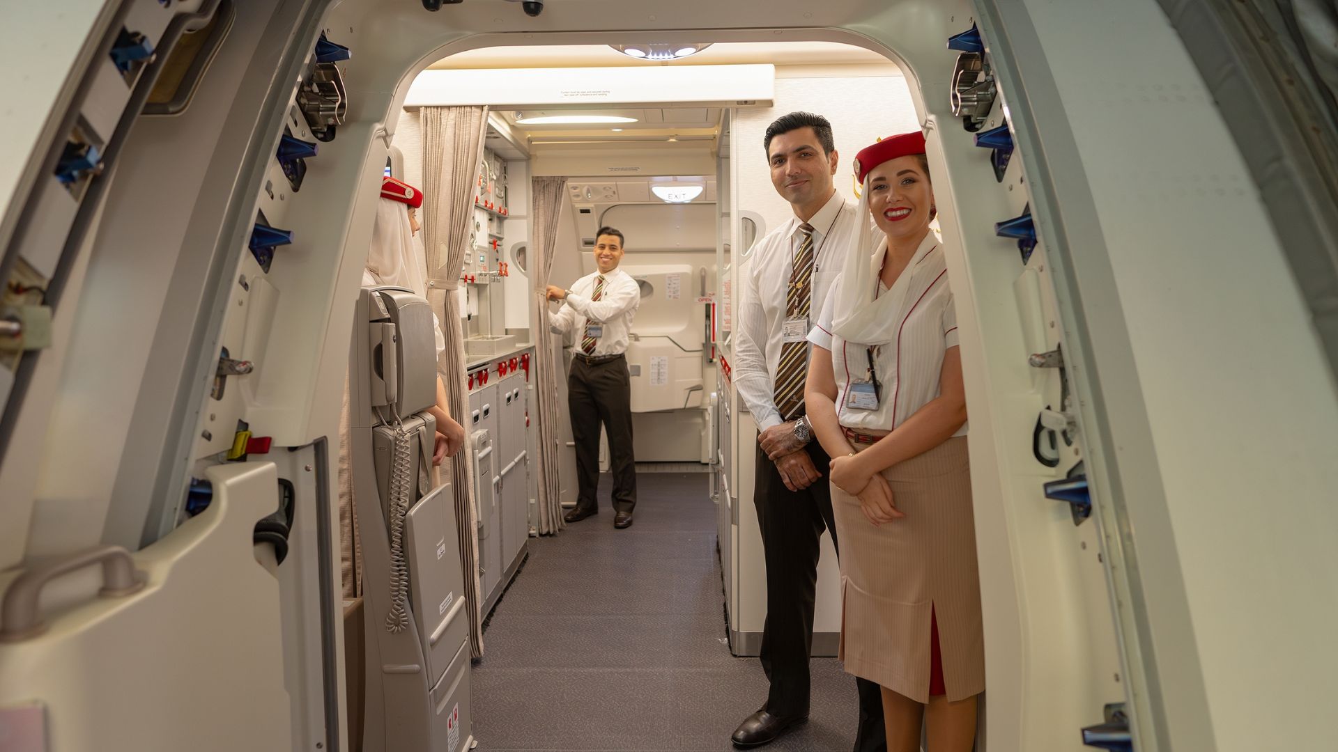 Three flight attendants are waiting for passengers to board the plane.
