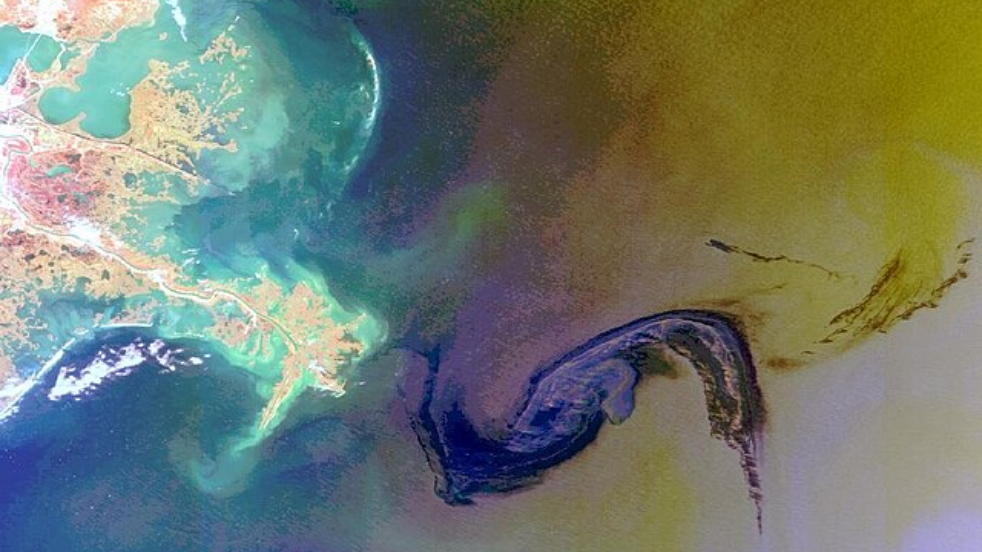 Large dark oil slick swirling on the surface of blue water in the Gulf of Mexico.