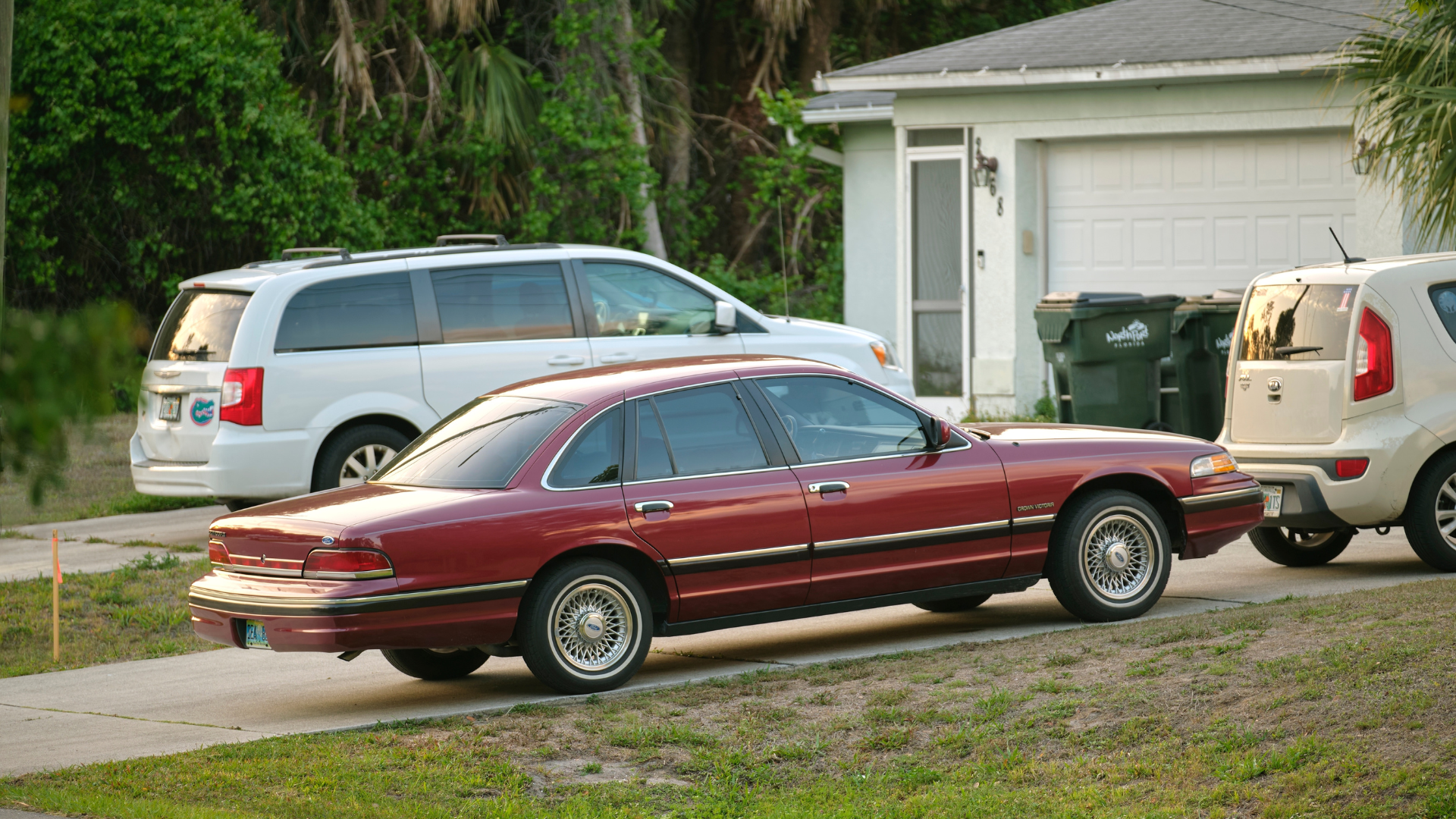 Car parked in front of wide garage double door on concrete driveway of new modern house.