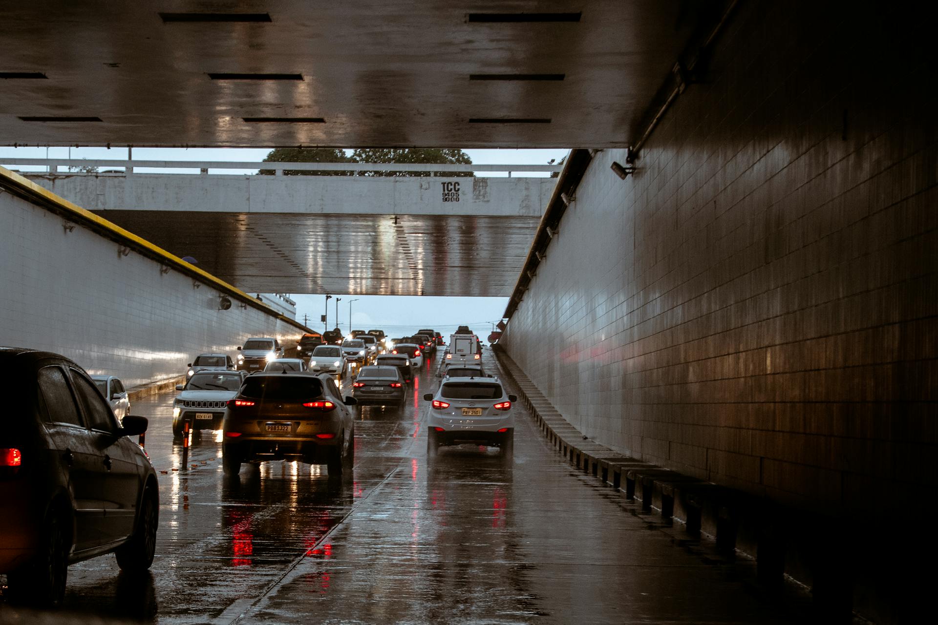 Cars driving through a flooded roadway tunnel during heavy rain.