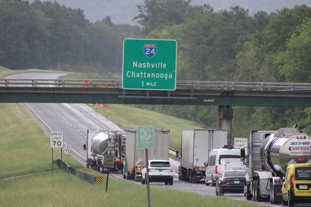 Interstate 24 highway sign for Nashville and Chattanooga above traffic on a rainy roadway.