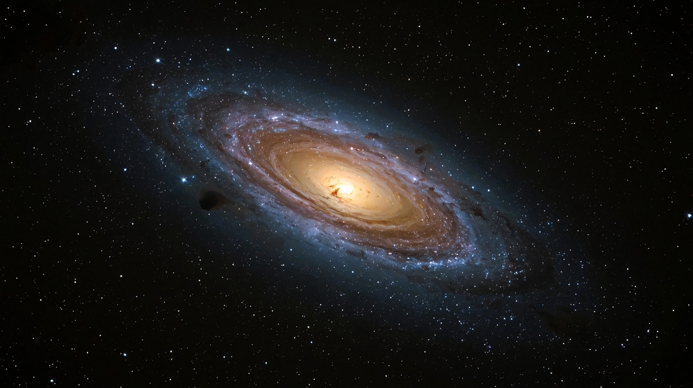 Spiral galaxy with a glowing golden core and sweeping dust lanes surrounded by dense star fields in deep space.