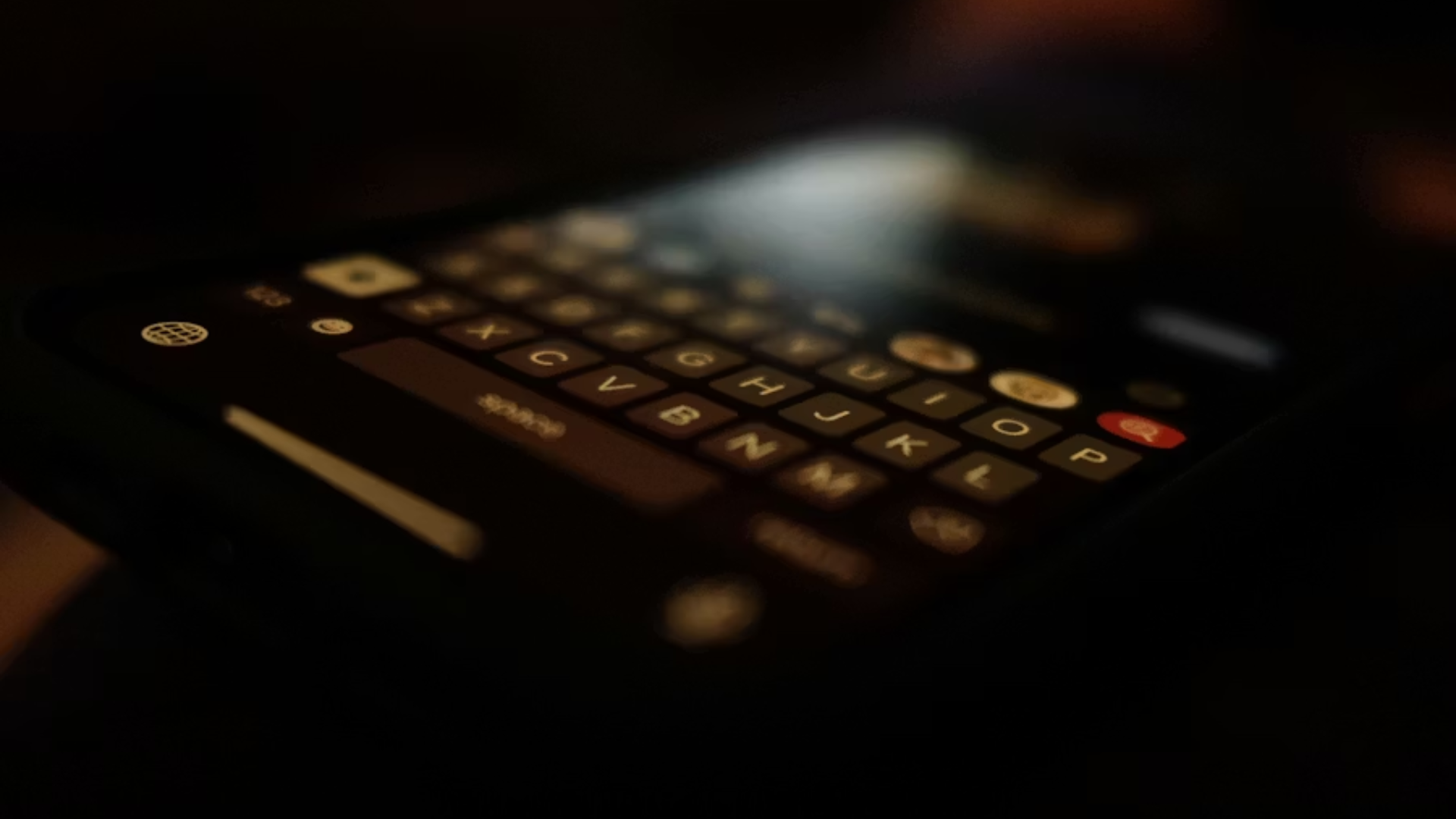 A close-up of a dark smartphone screen showing a glowing digital keyboard in soft focus, symbolizing digital communication or evidence.