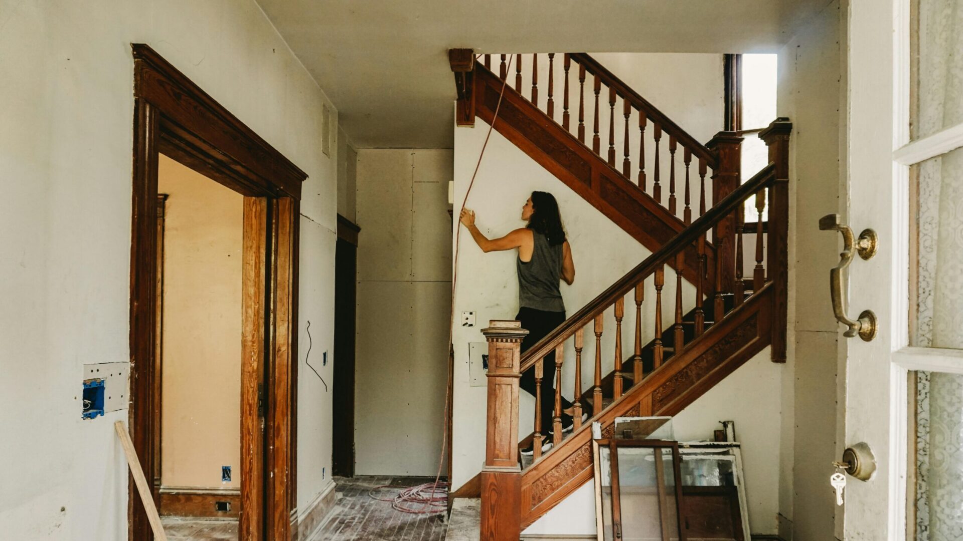 Person standing on a wooden staircase inside a home during renovation work.