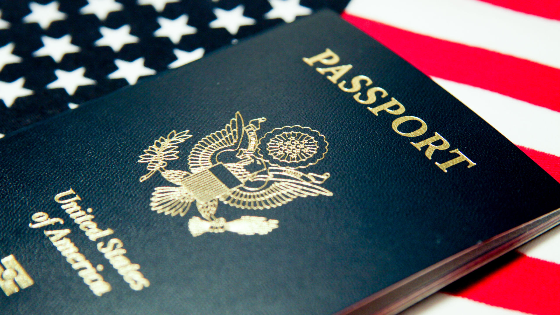 A dark blue United States passport rests on top of an American flag.