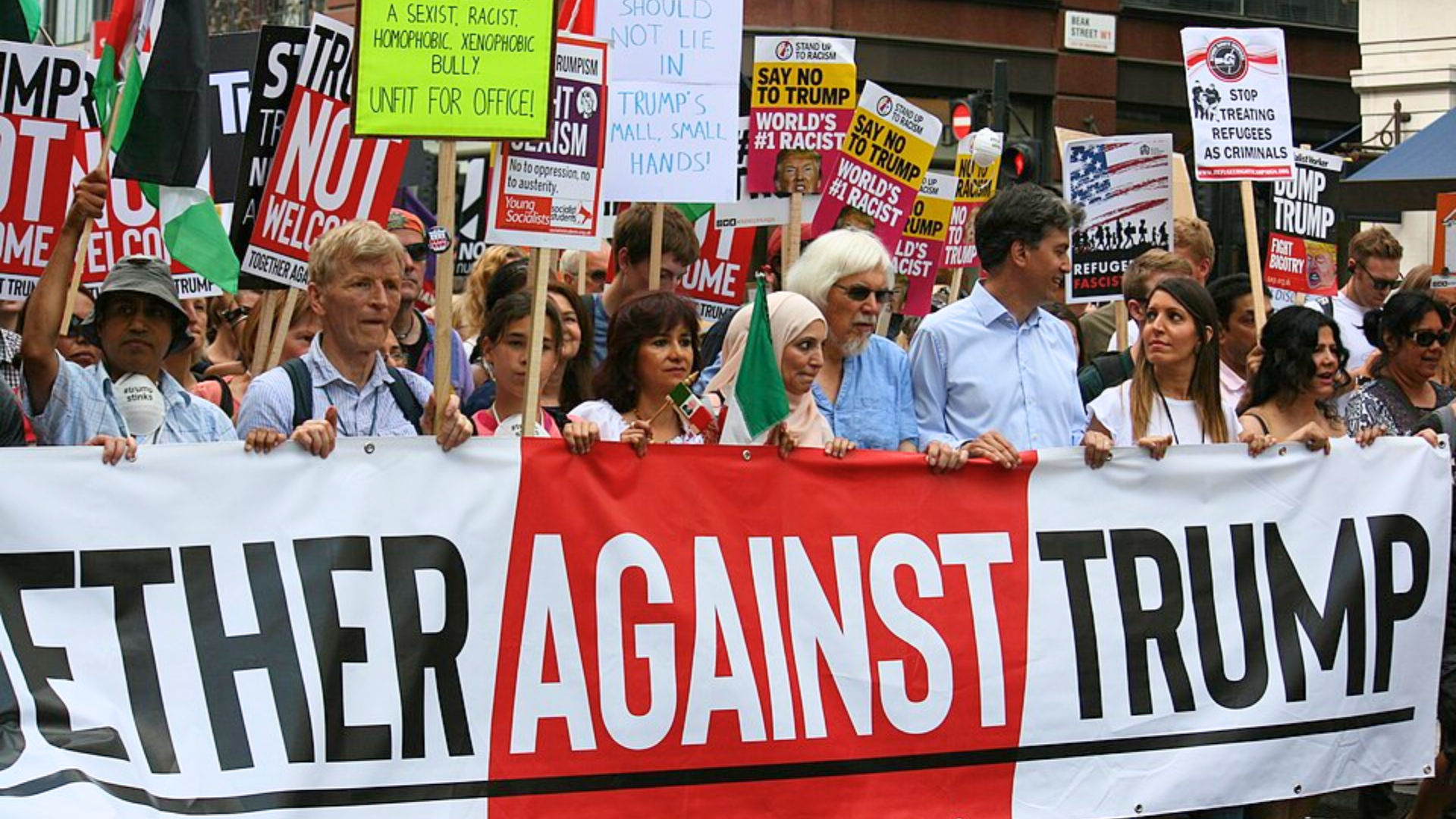 A crowd of people marching and holding various signs during an anti-Trump protest