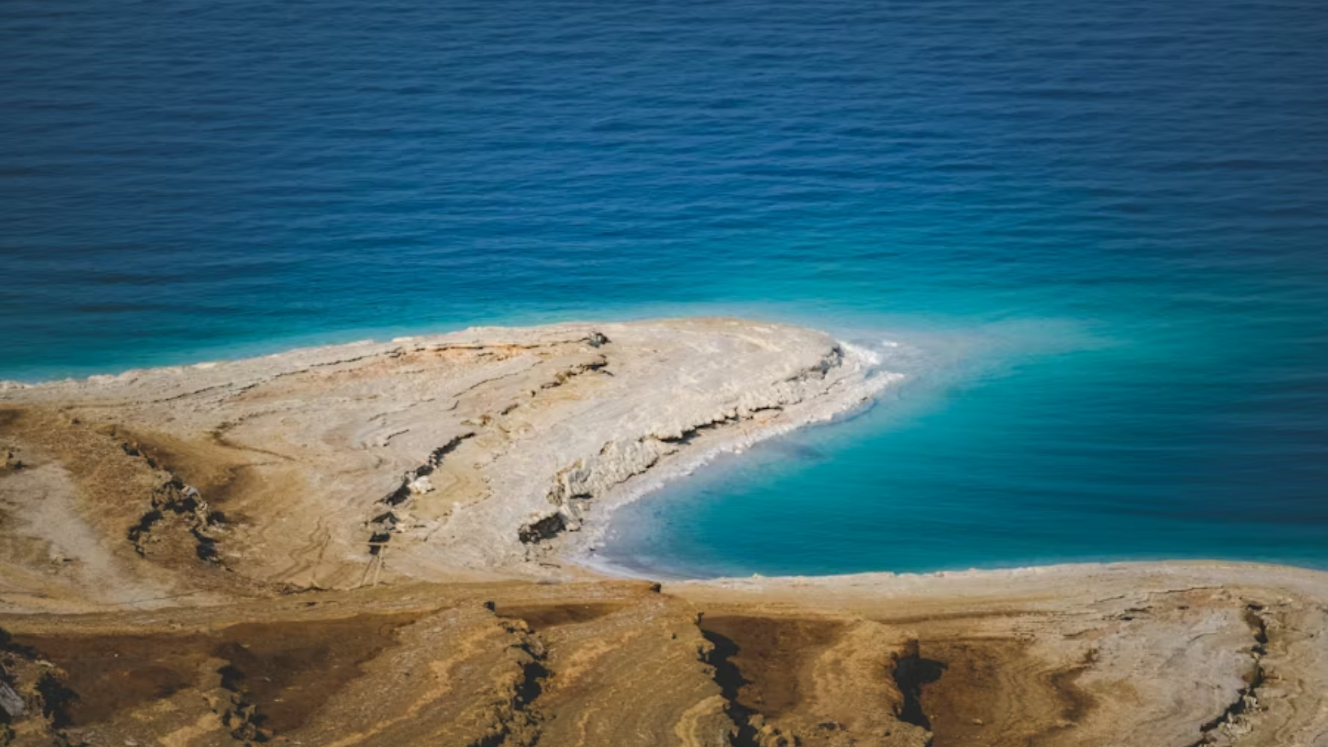 A high-angle scenic shot of a rocky coastline meeting the deep blue ocean.