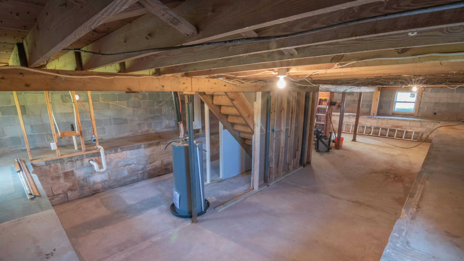 Unfinished basement with exposed wooden beams, concrete floor, and support columns.