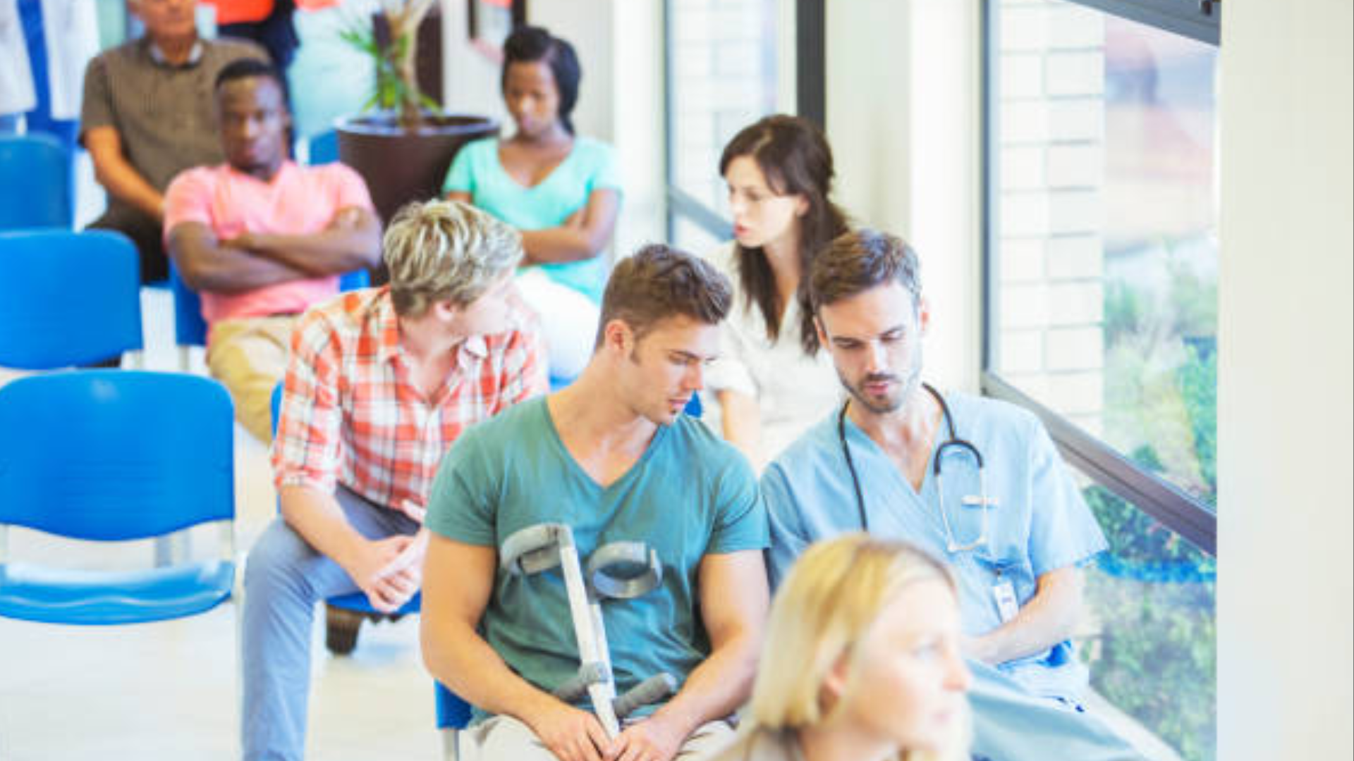 A busy hospital waiting room where several people are seated.