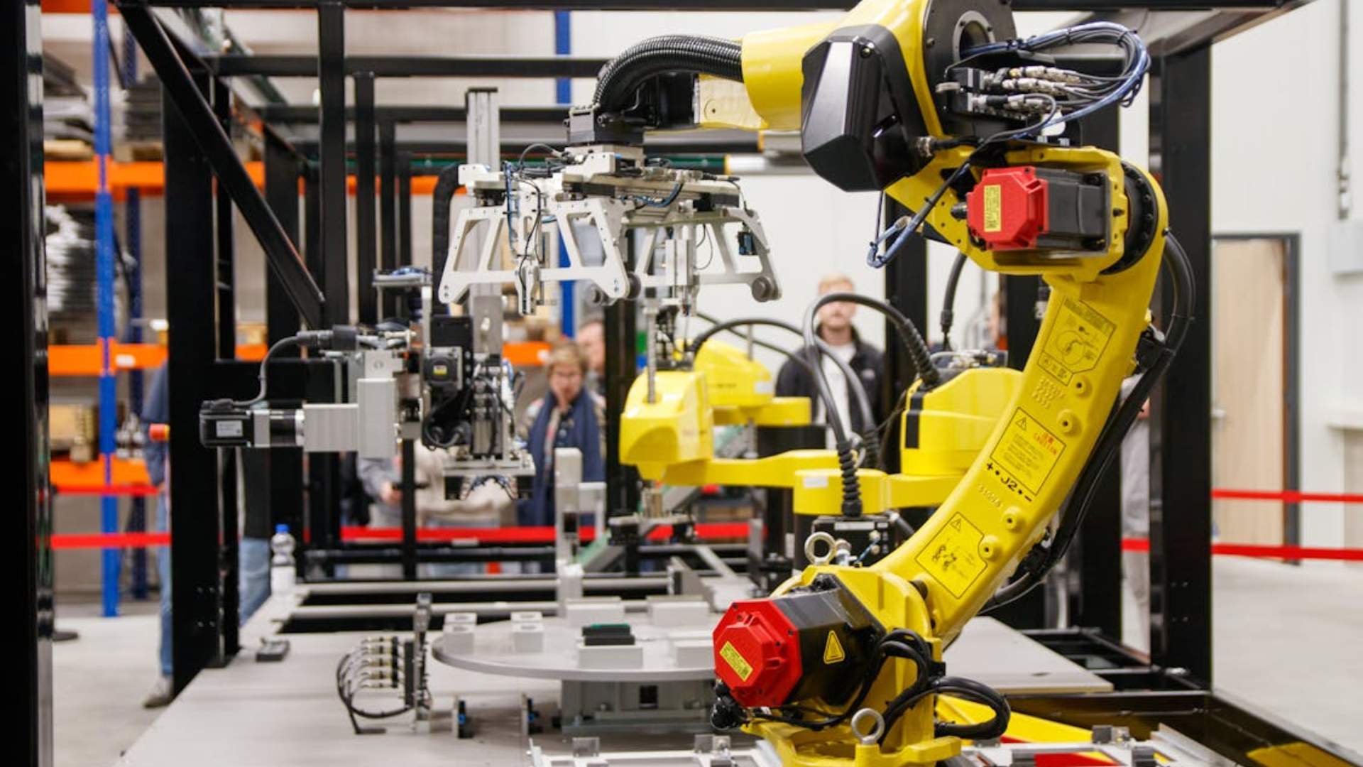 Bright yellow robotic arms operate on an assembly line inside an industrial factory.