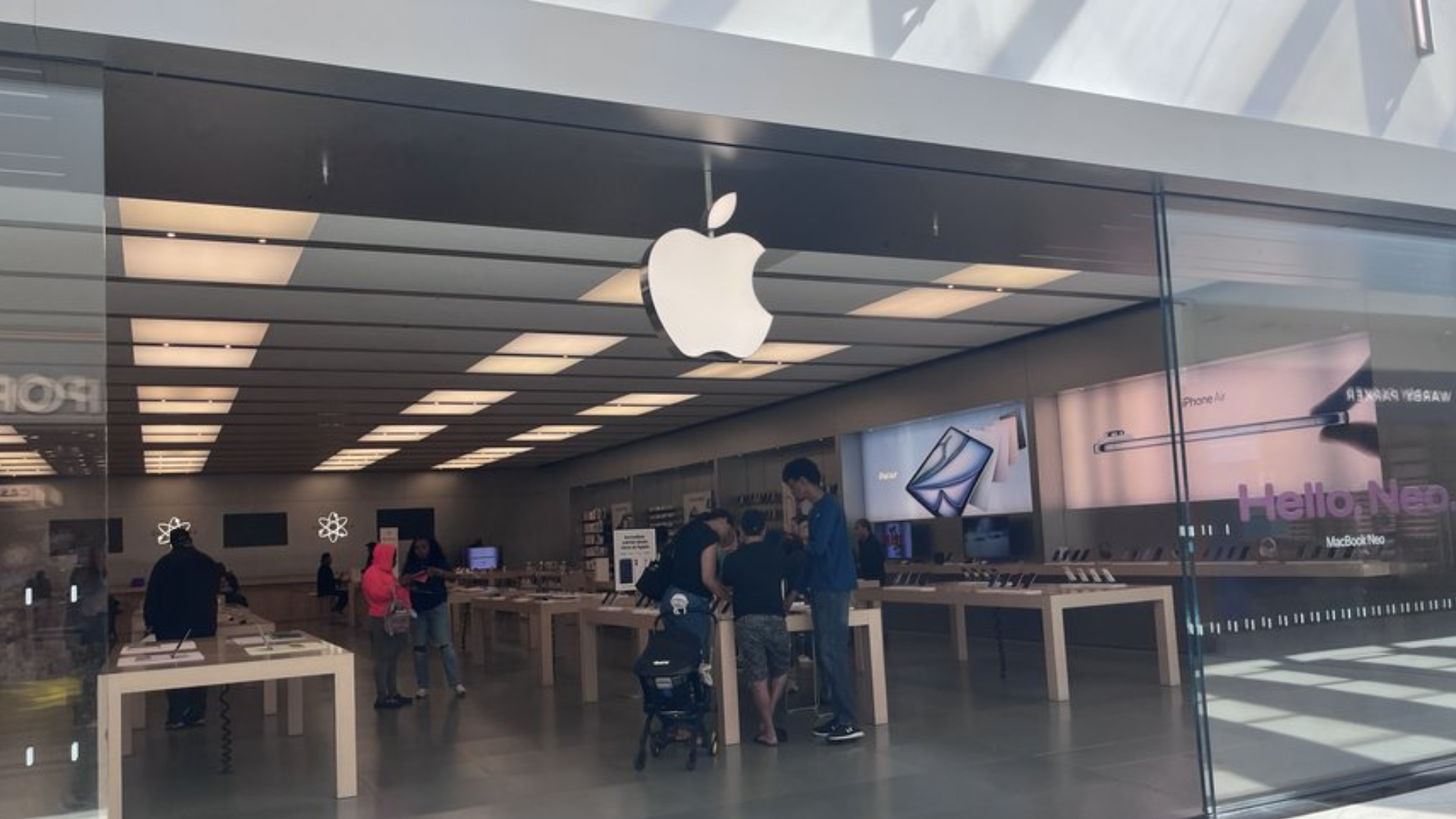 A wide-angle interior view of a modern Apple Store inside a shopping mall.