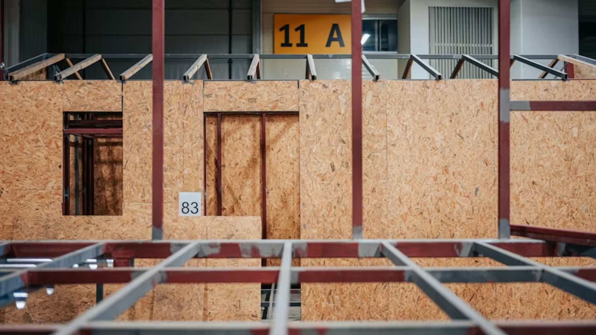 A close-up interior view of a modular or factory-built home under construction; the frame is made of steel and wood.