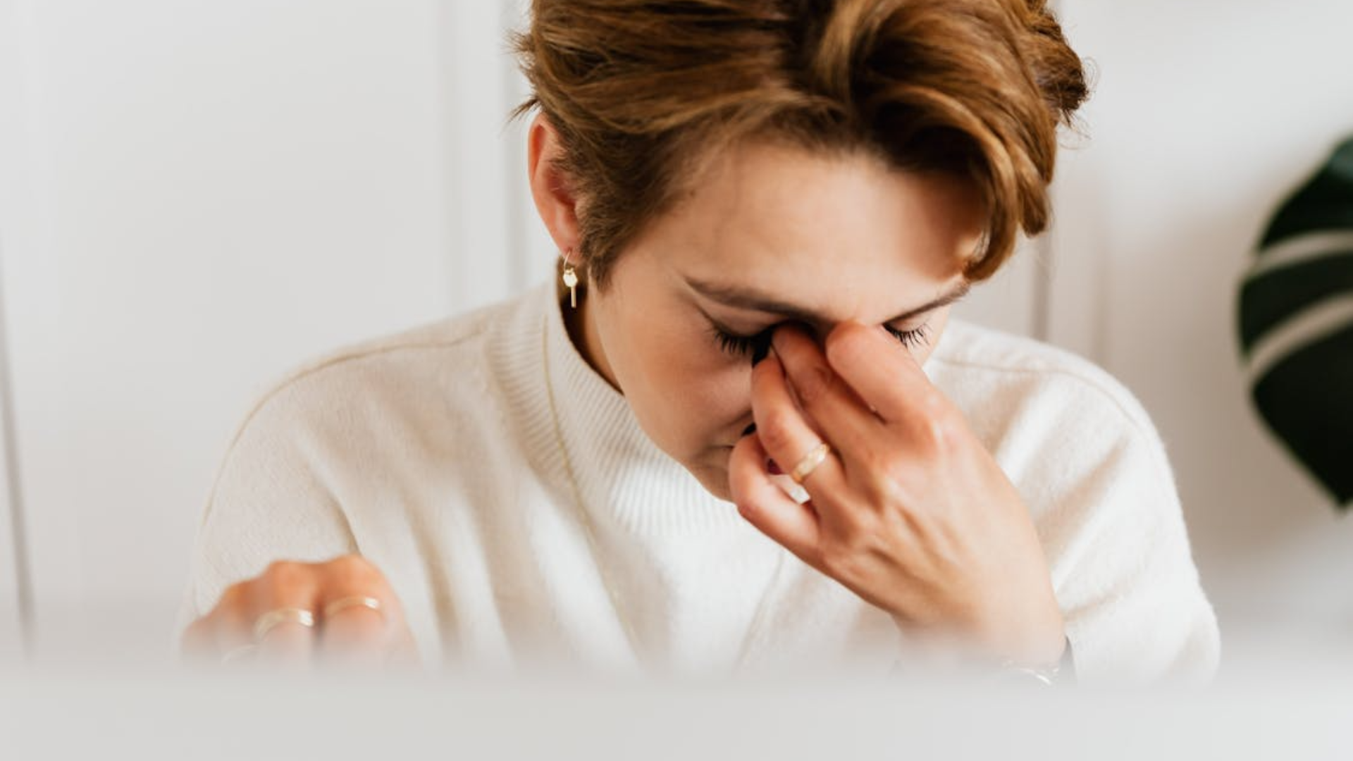 A person rubs their eyes and looks tired.