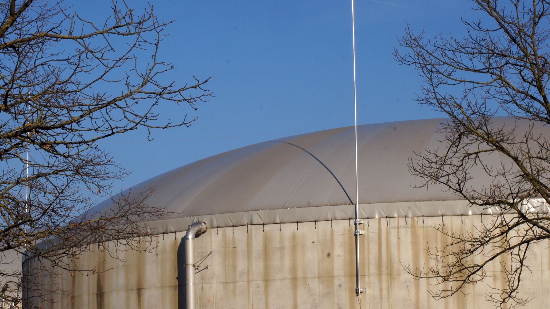 Big nuclear waste dome near the shore, and surrounded by trees.