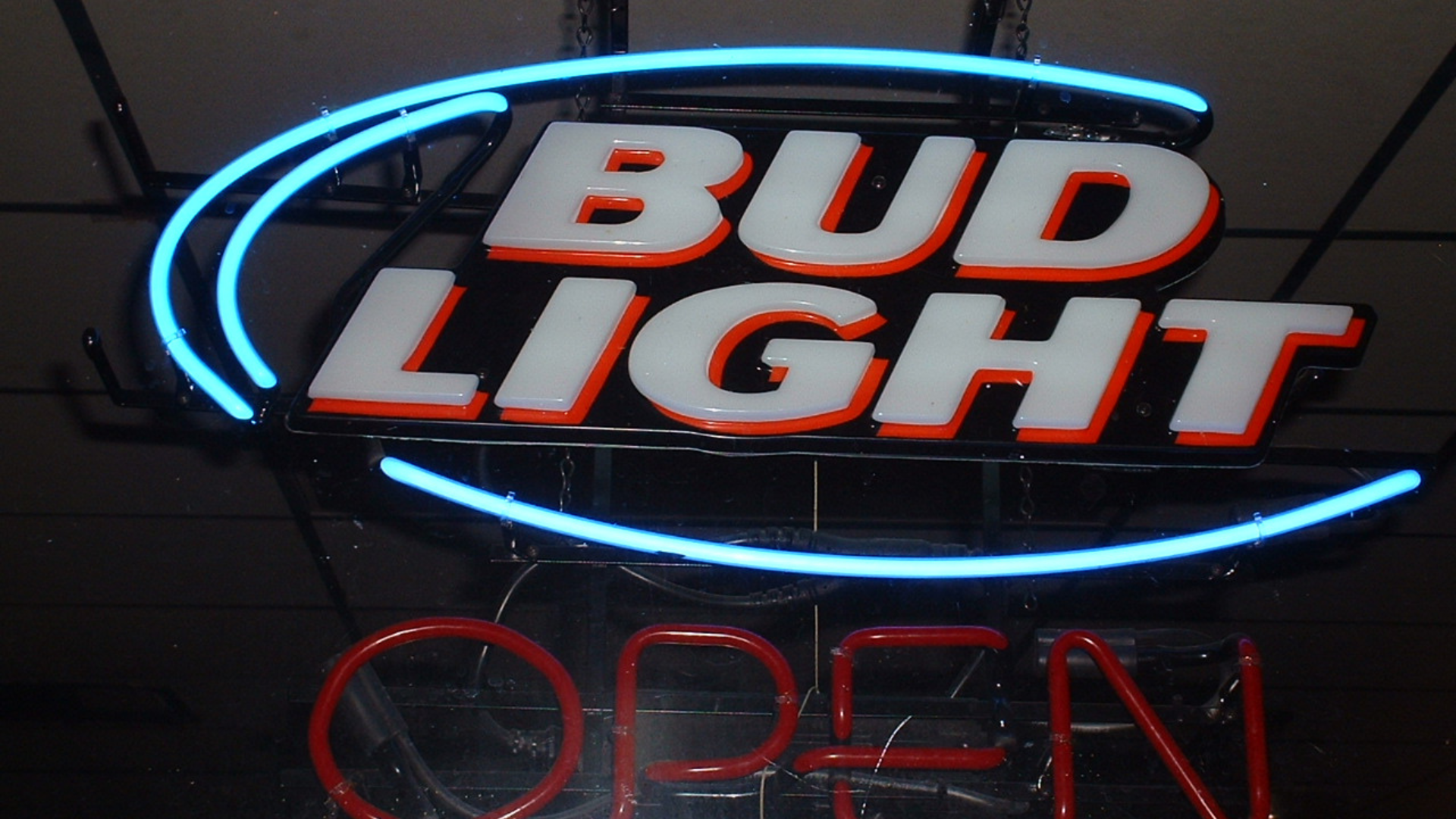 A glowing neon sign displays the _Bud Light_ logo in white and blue above a red neon _OPEN_ sign.