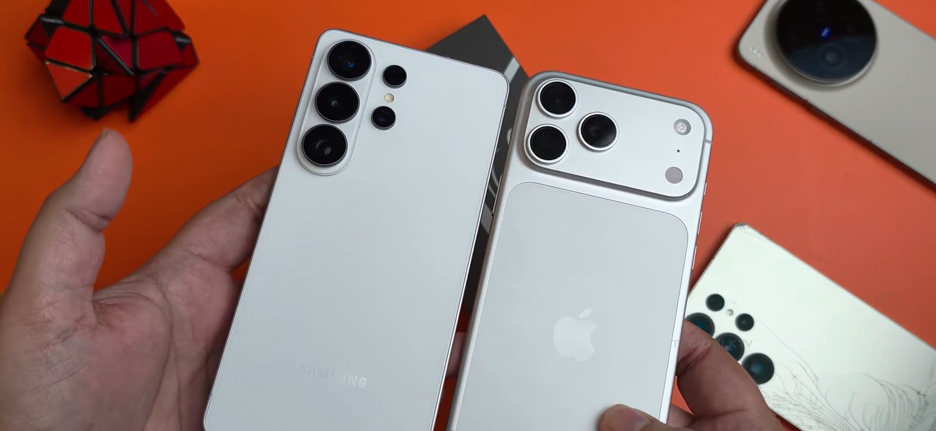 Samsung Galaxy S26 Ultra smartphone and Apple iPhone 17 Pro Max held side by side showing rear camera arrays.