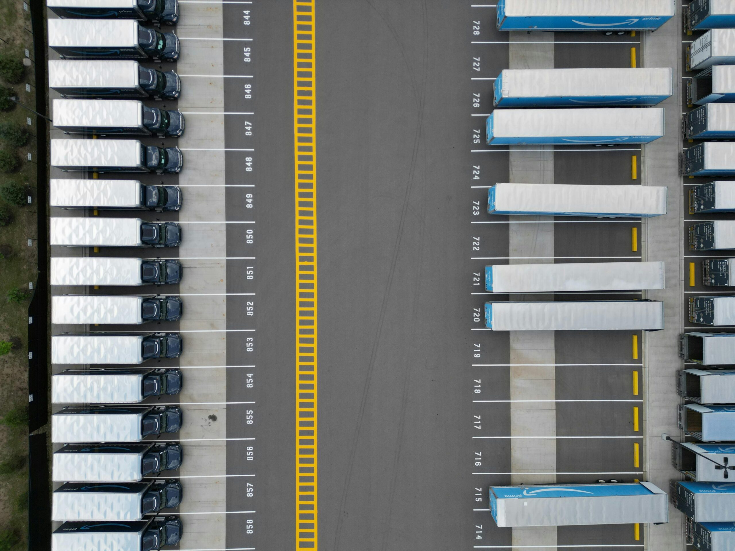 Aerial view of delivery vans and trailers parked in rows at a logistics facility.