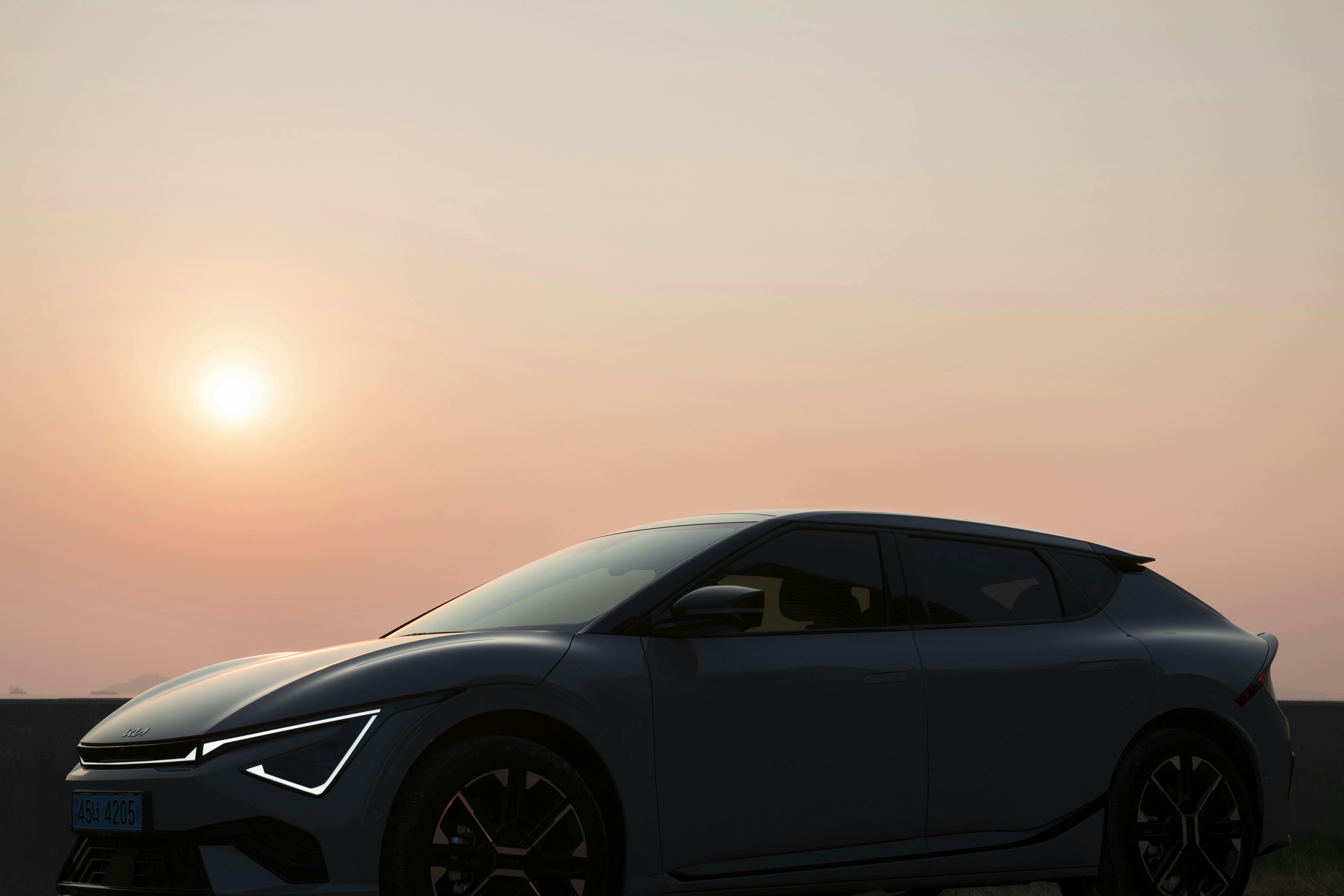 Electric car parked at sunset with sun low on the horizon in the background.