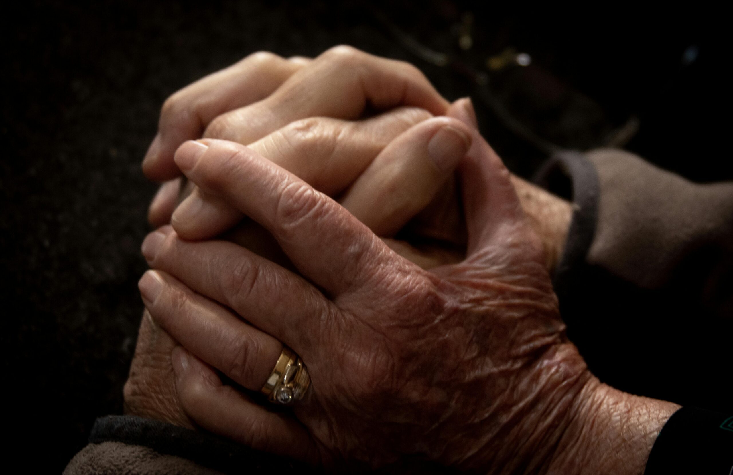 Elderly hands clasped together, showing comfort and support.