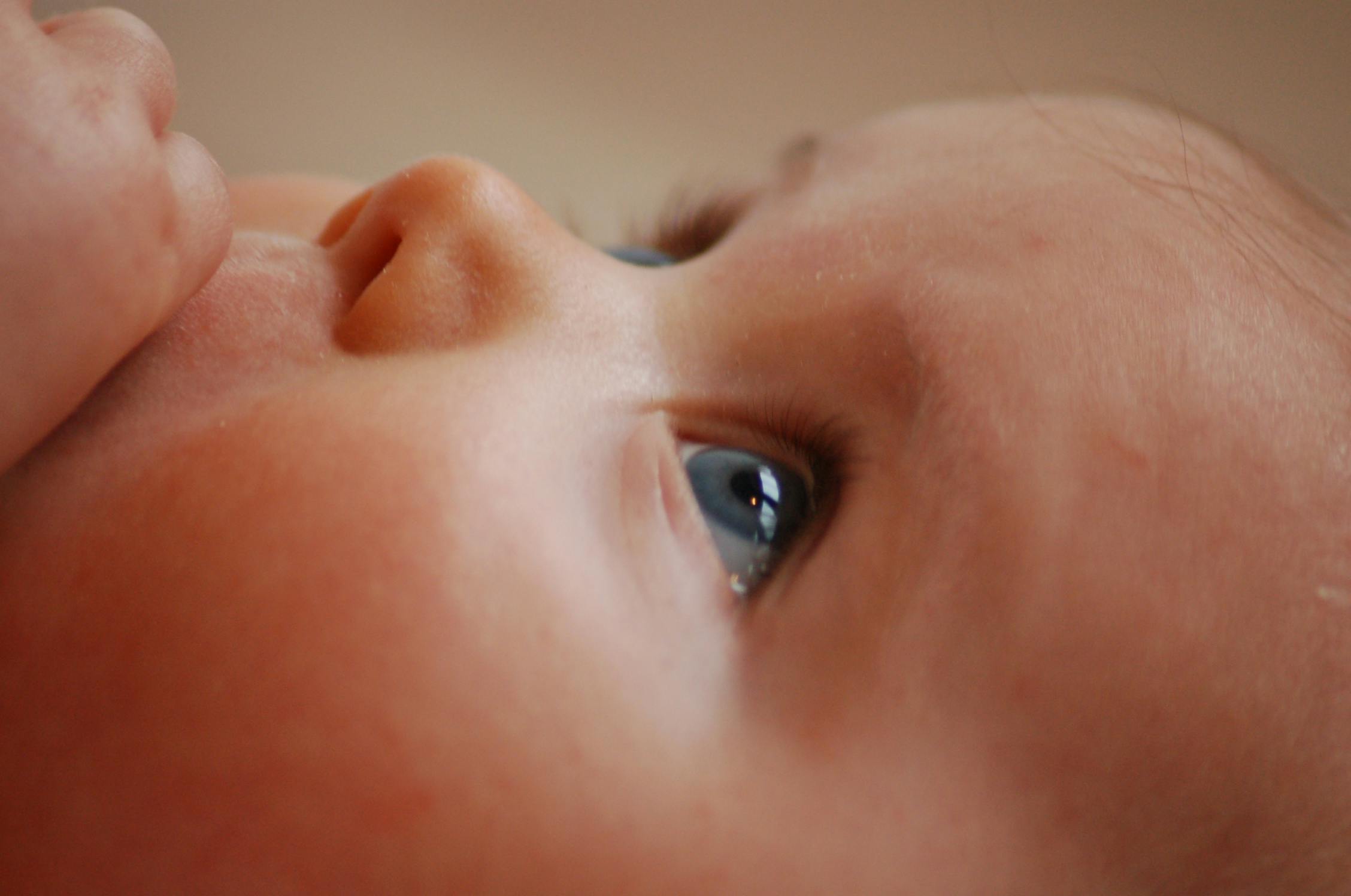 Close-up of a baby’s face focusing on one eye and cheek.