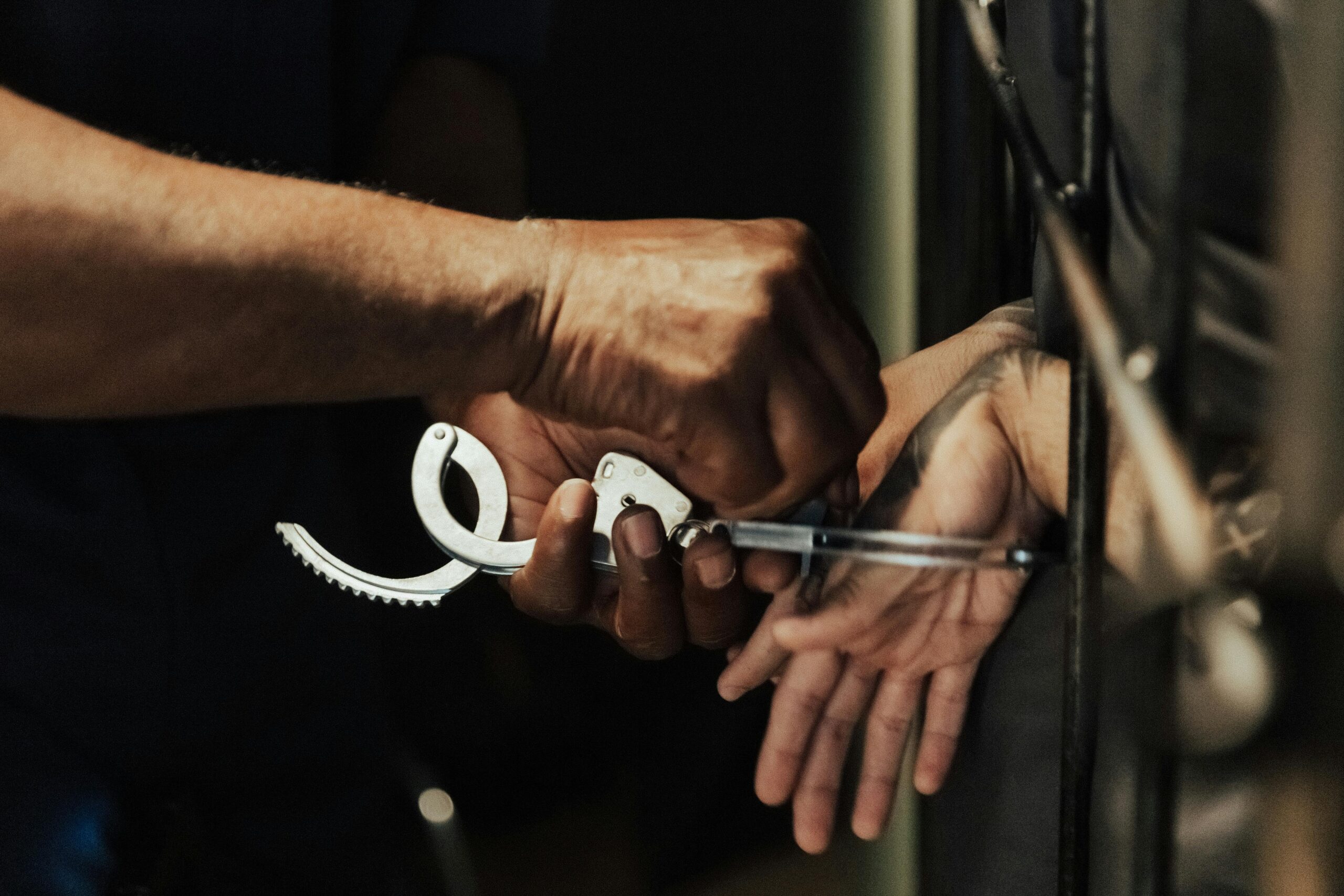 Police officer placing handcuffs on a person’s wrists during an arrest.