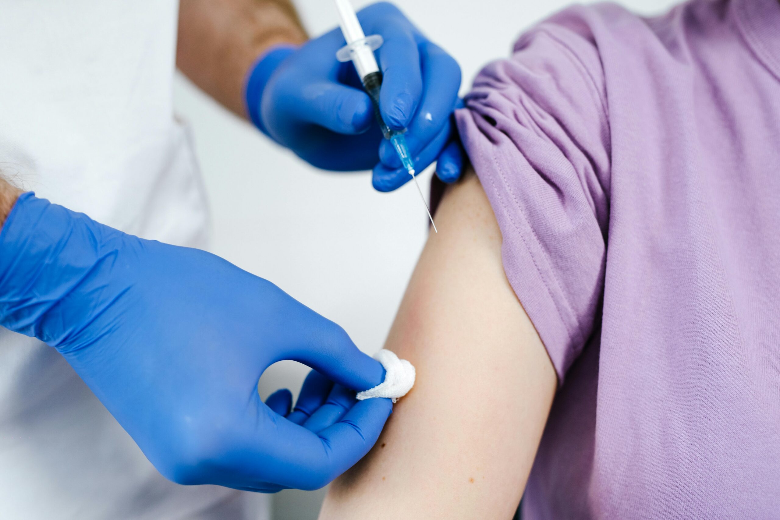 Healthcare worker administering a vaccine injection into a patient’s upper arm.