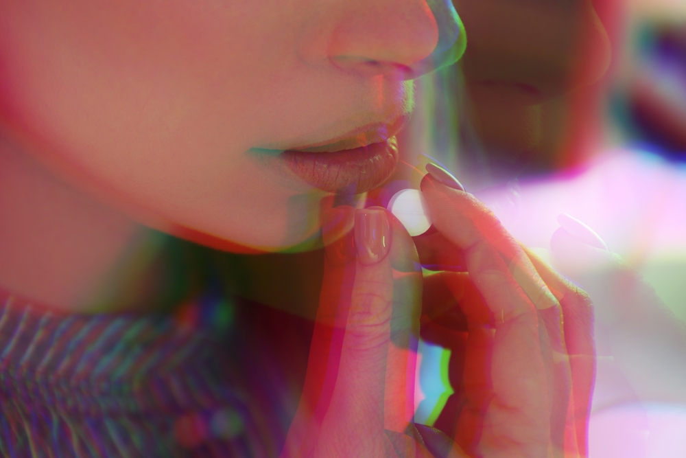 Woman taking pill in close-up with psychedelic glitch effect suggesting hallucinations.