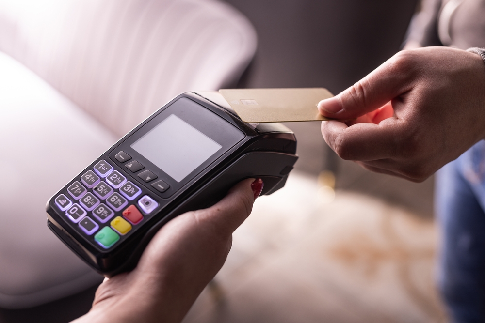 Person inserting credit card into payment terminal during in-person transaction.