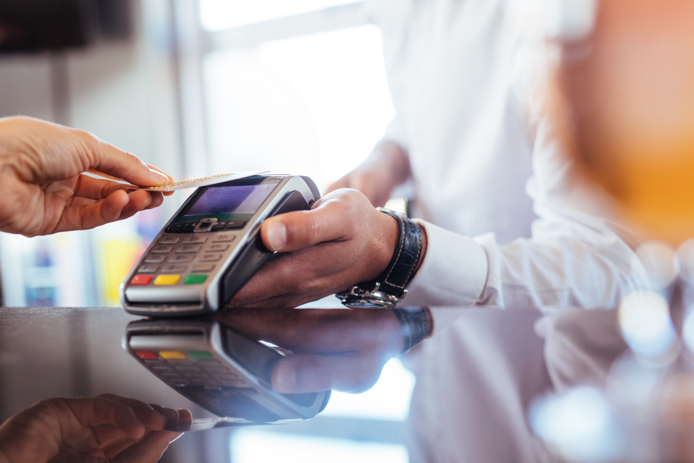 Customer tapping credit card on payment terminal during in-store transaction.