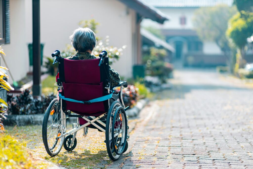 Elderly person in a wheelchair moving along a residential path.