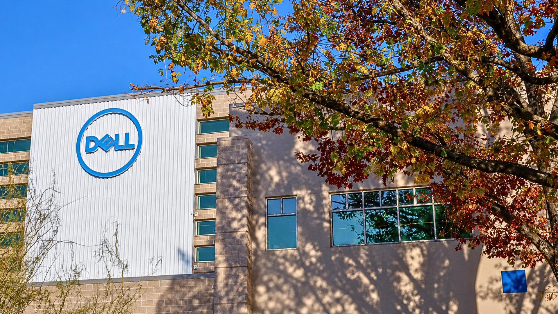 A daytime shot of a modern Dell corporate building featuring a large, blue circular 