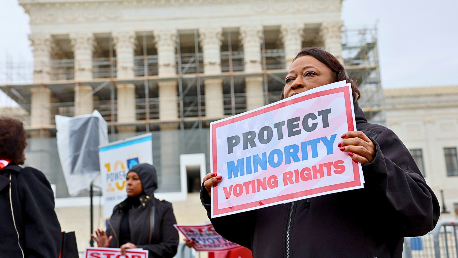A close-up shot of a woman holding a protest sign that reads 