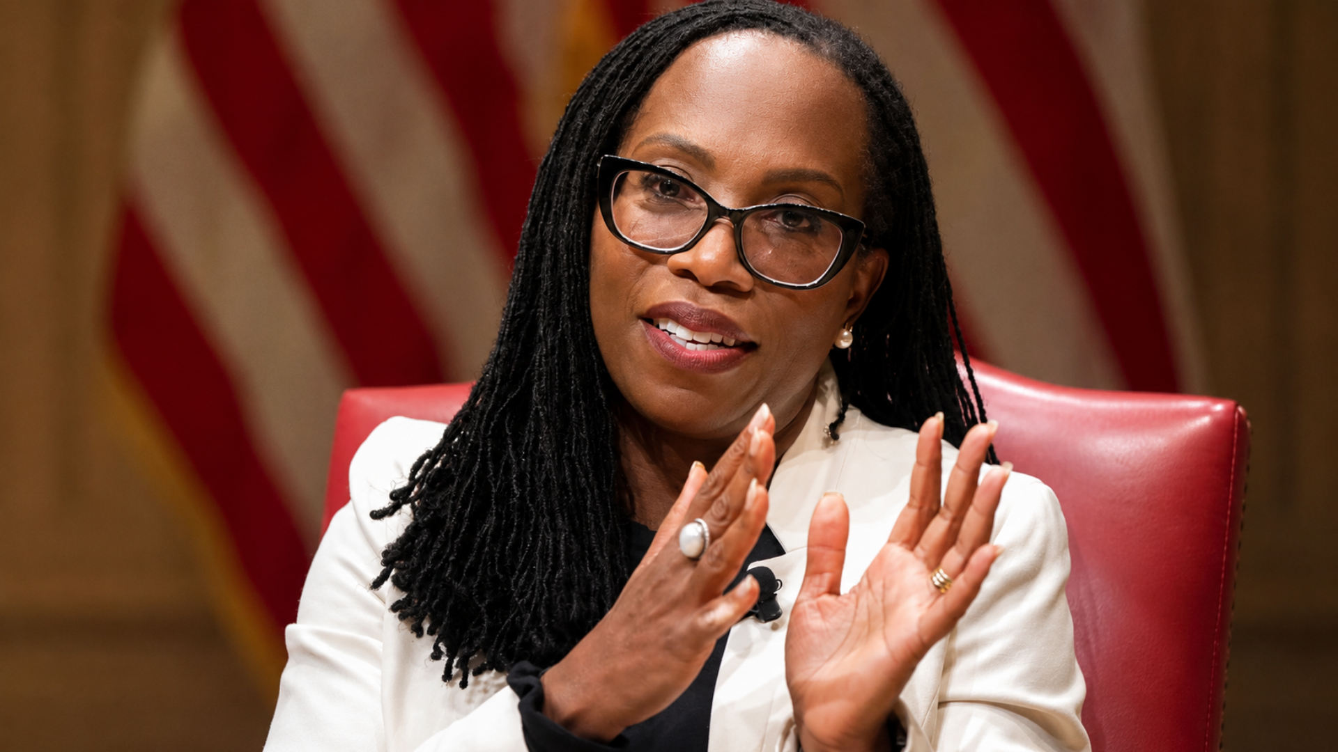 A medium shot of Justice Ketanji Brown Jackson speaking expressively with both hands raised.