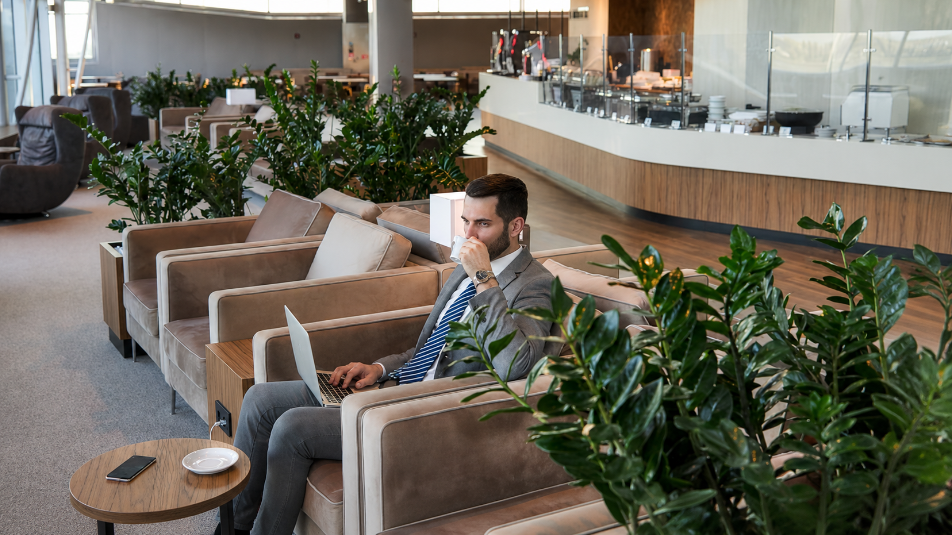 Business traveler working on laptop while seated in an airport lounge.