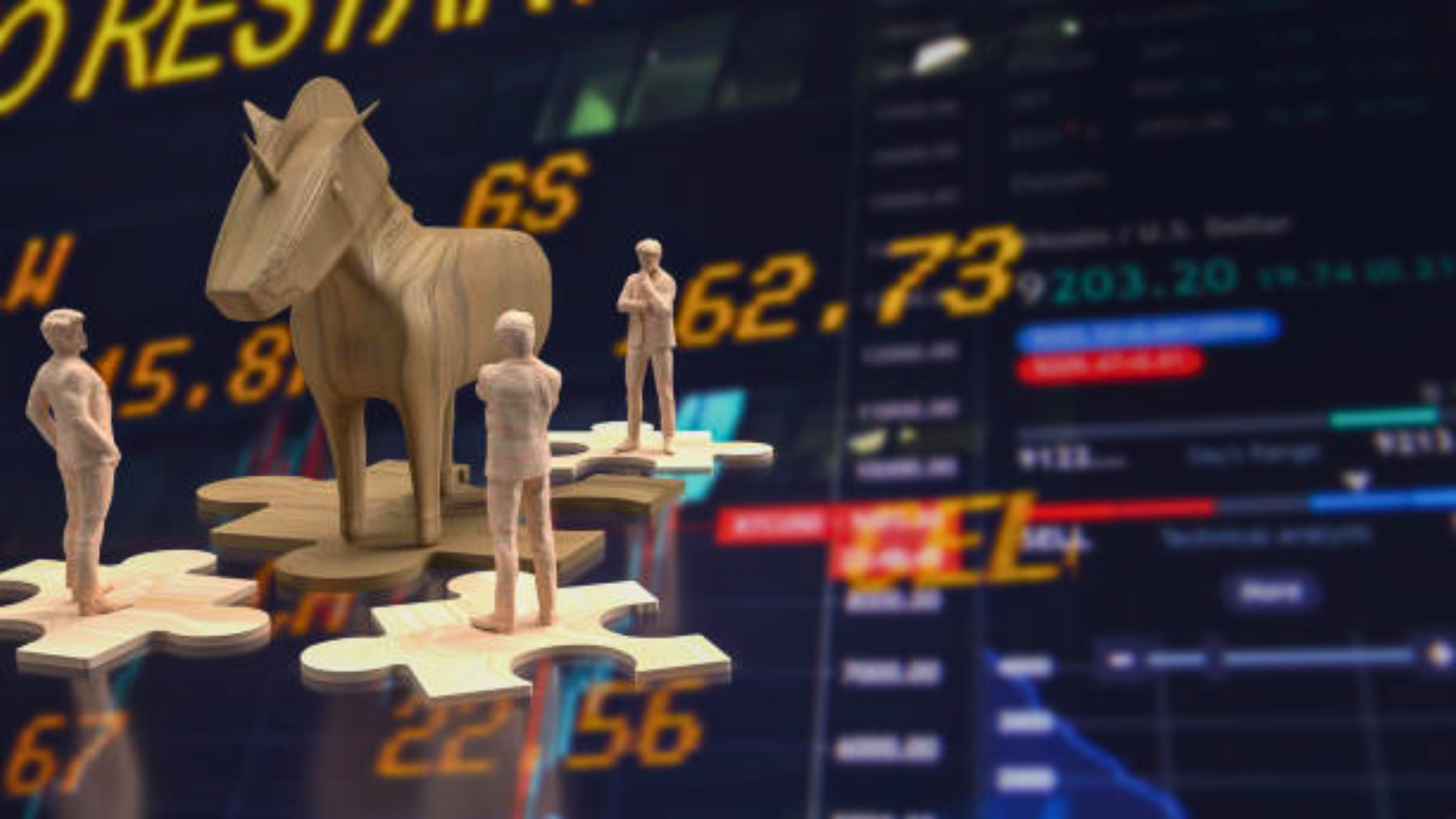 A miniature wooden unicorn figure standing on puzzle pieces alongside tiny human figures, set against a blurry digital stock market data screen.