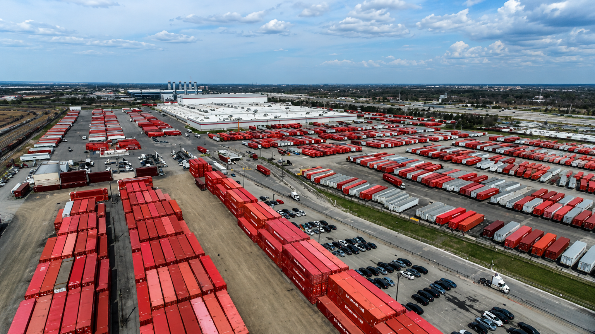 Aerial view of shipping containers and freight trailers at a logistics hub.