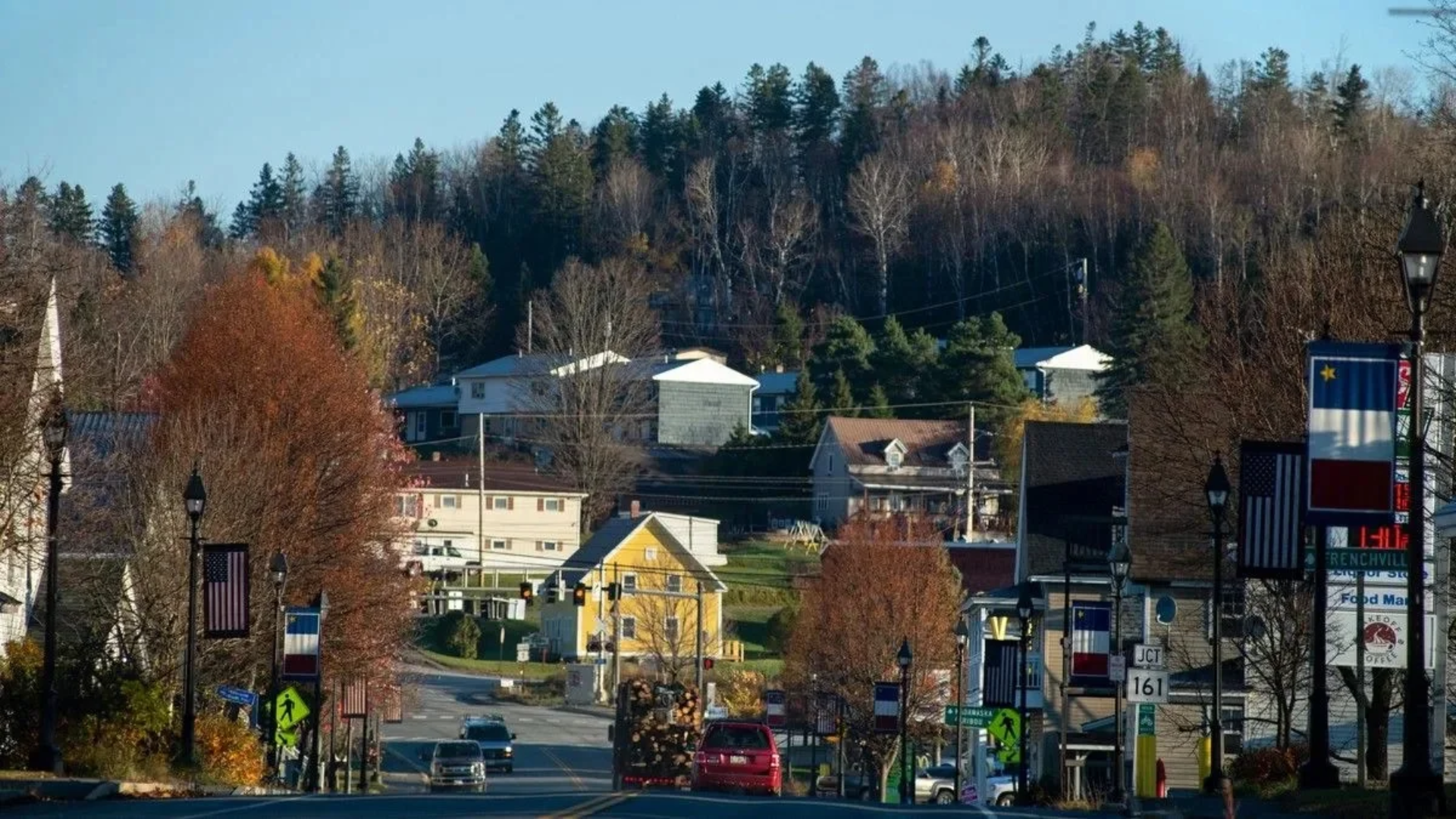 Small town near the U.S.-Canada border with Acadian and American flags displayed along the street.