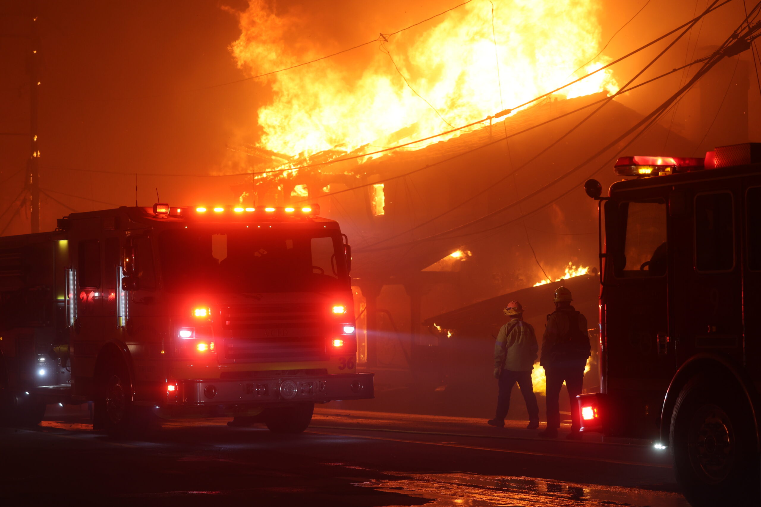 Firefighters respond to a large building fire at Los Angeles with flames engulfing the structure at night.