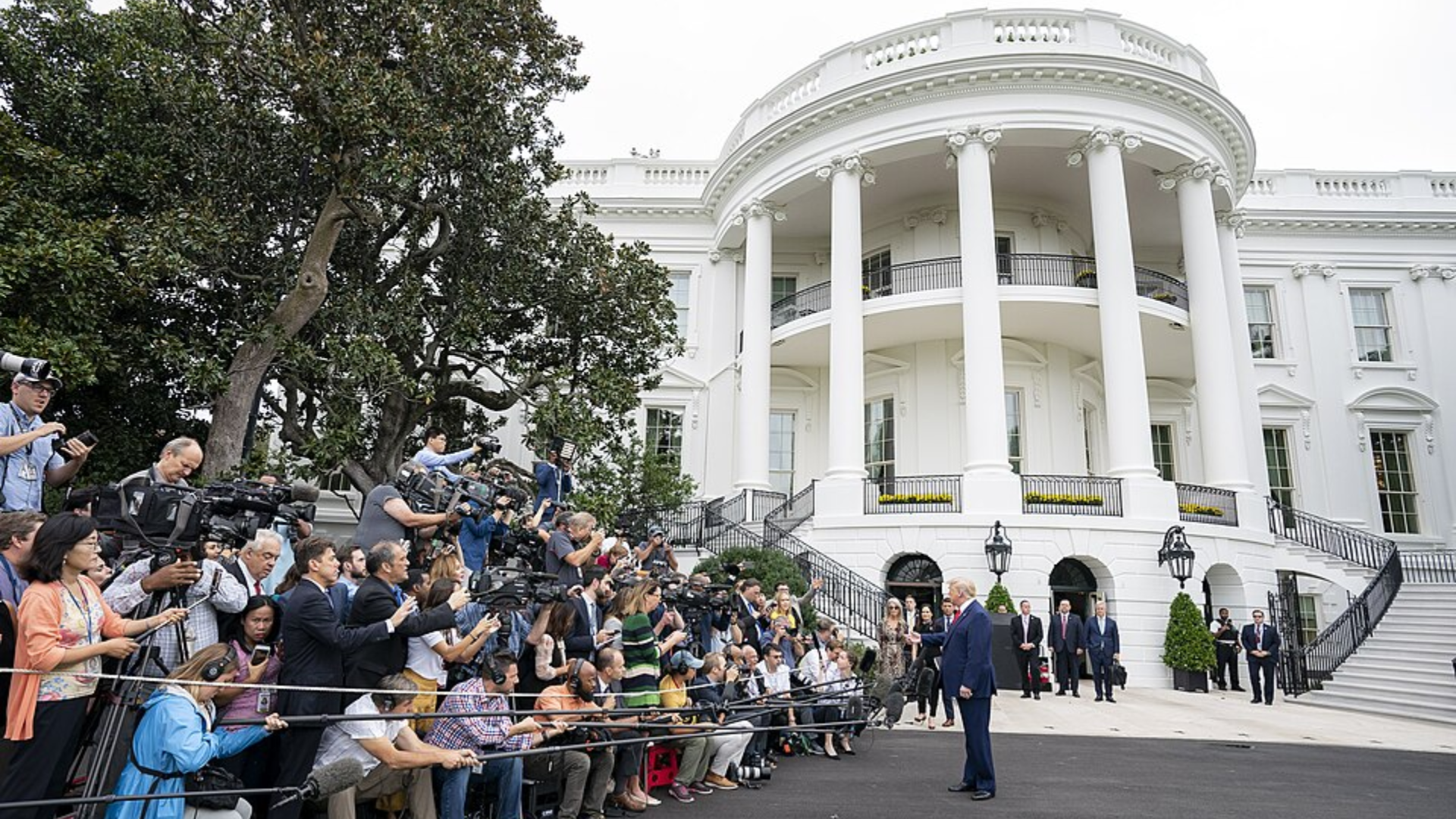 Donald Trump speaks to a large group of reporters and camera crews outside the White House.