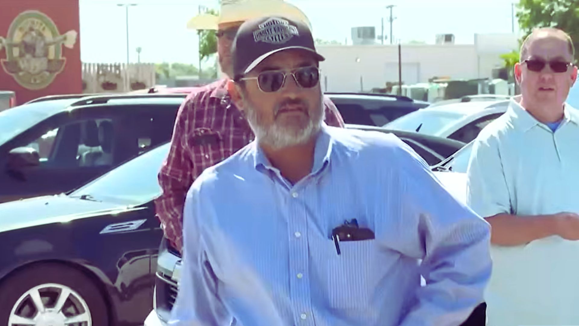 Former Kansas mayor Joe Ceballos stands outdoors while speaking with people near a parking lot.