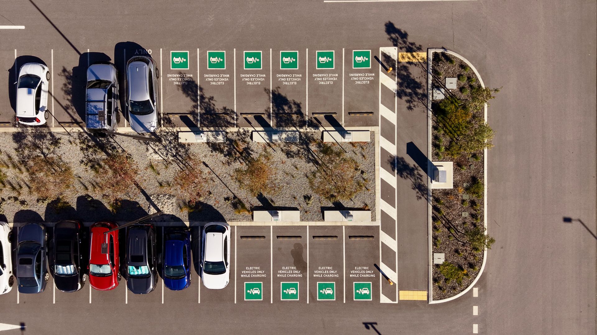 Top view of electric vehicle charging parking bays with EV symbols in modern urban car park.
