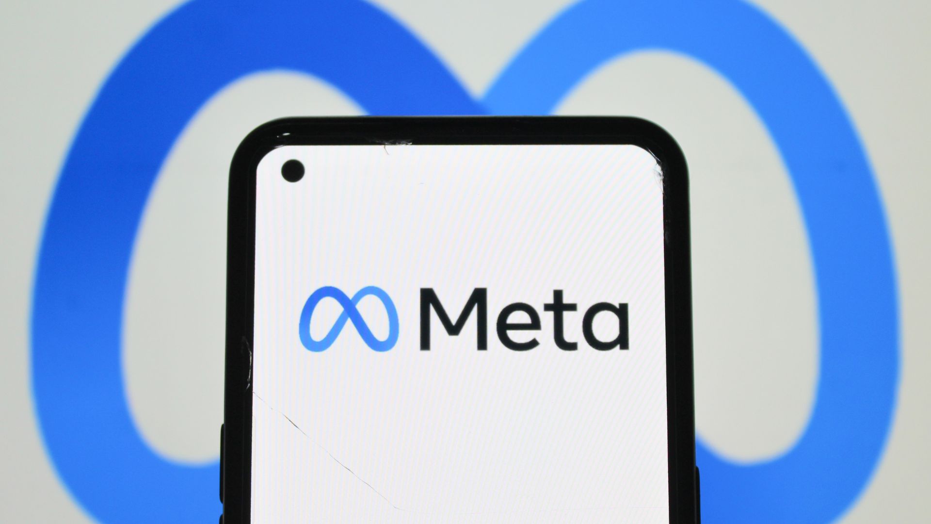 Meta logo displayed on a smartphone screen against a blue Meta background.