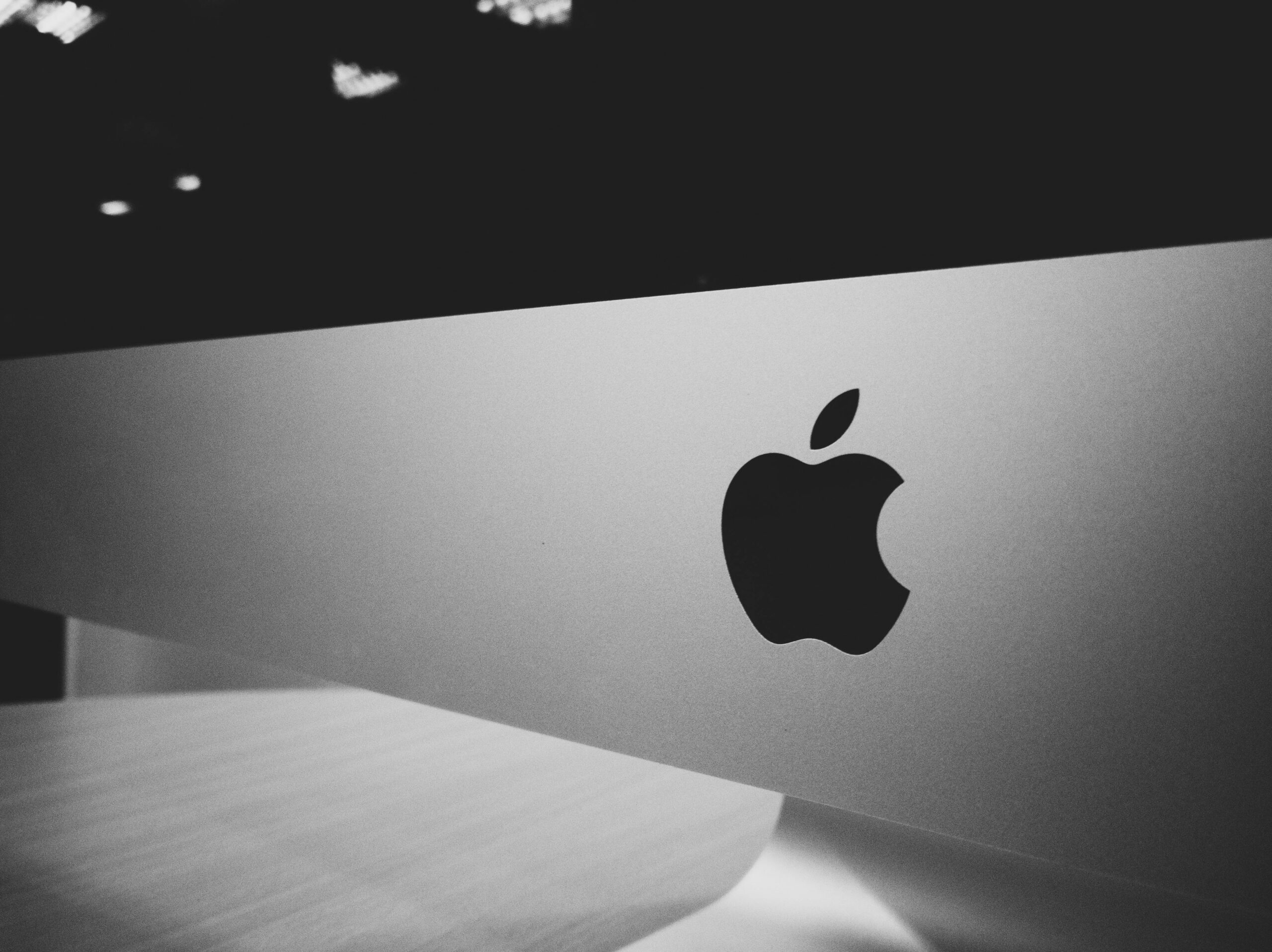 Apple logo displayed on the back of an iMac computer in a black-and-white close-up photo.