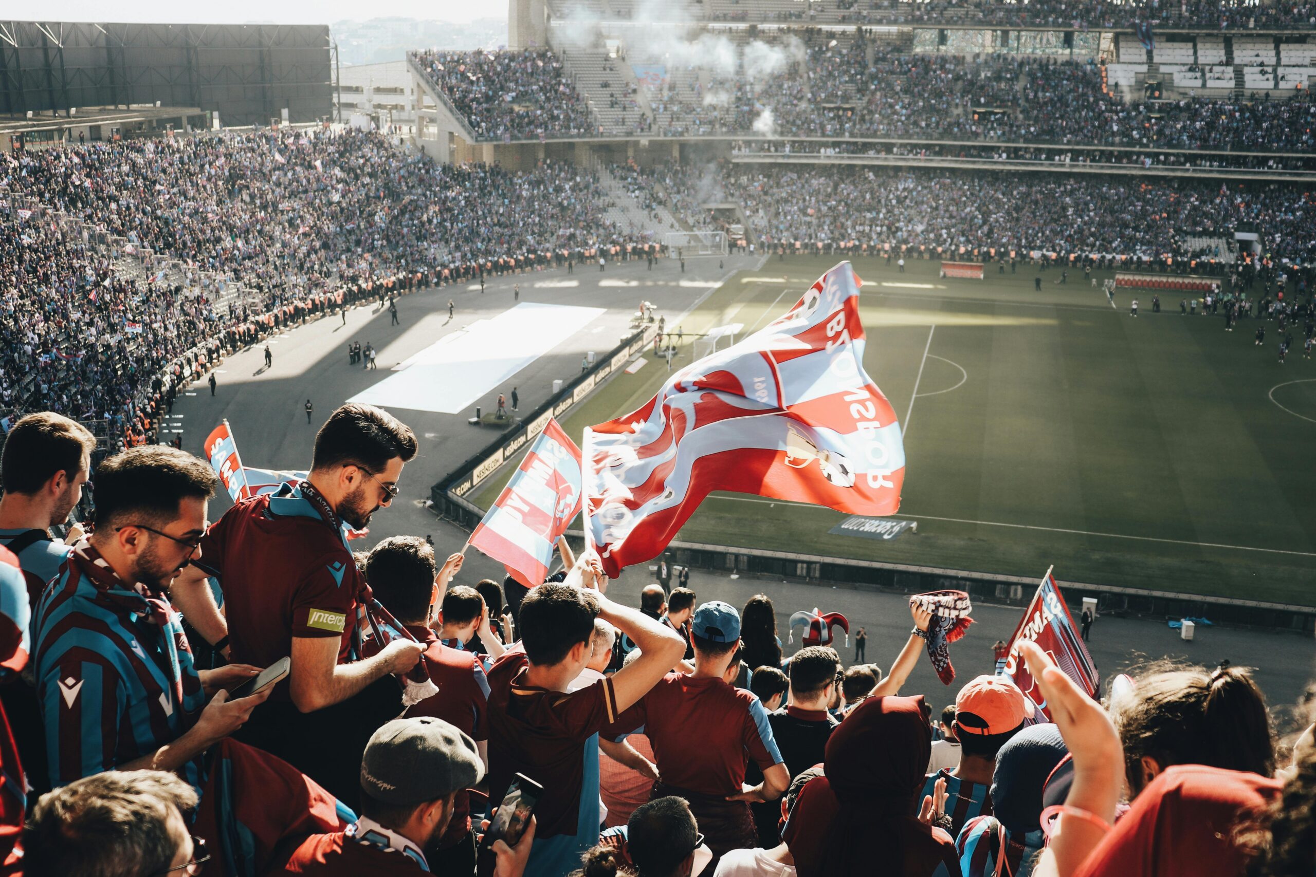 Soccer fans fill a packed stadium while waving team flags during a major international match.