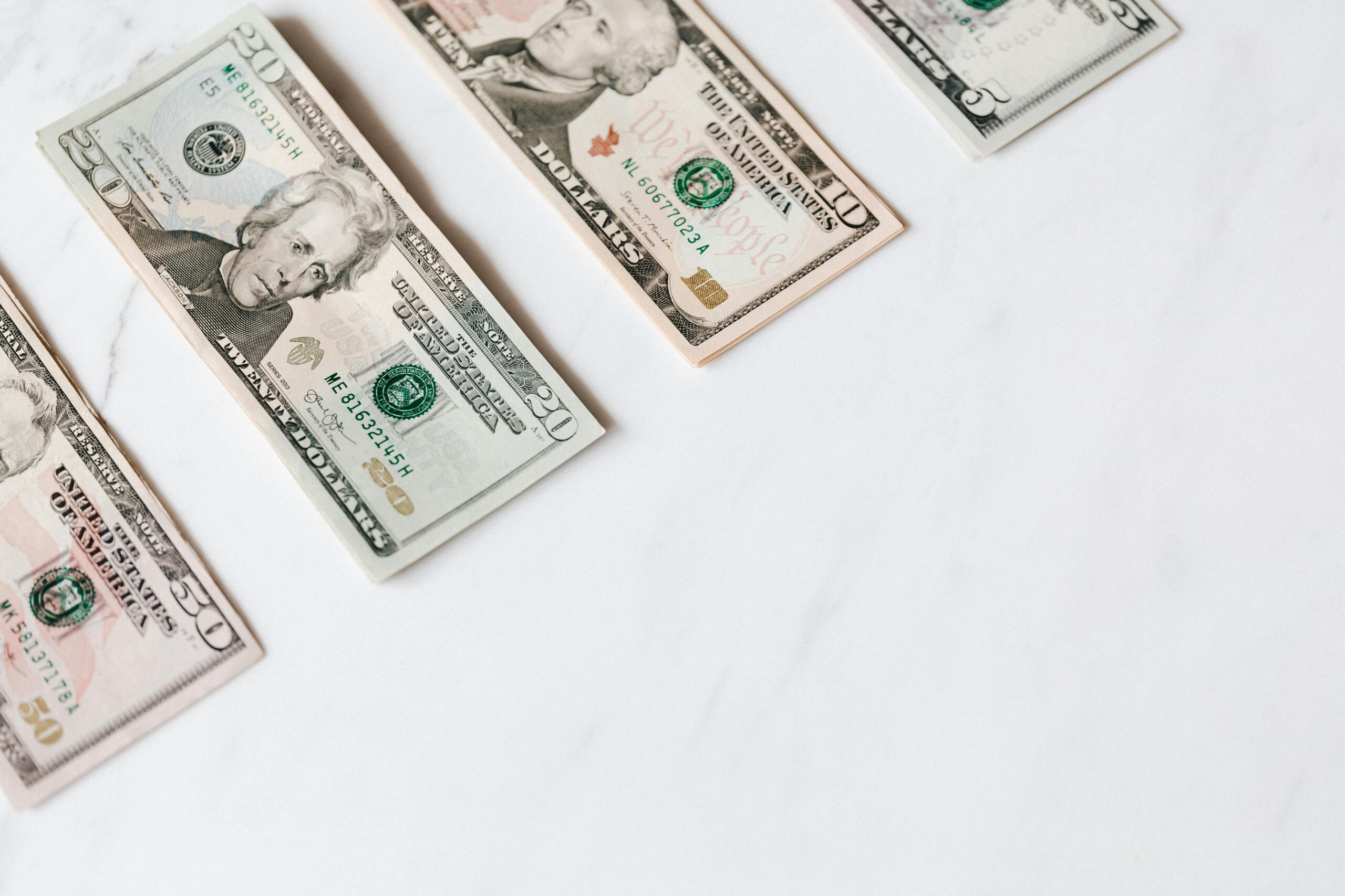 U.S. dollar bills including $20 and $10 notes arranged on a white surface.